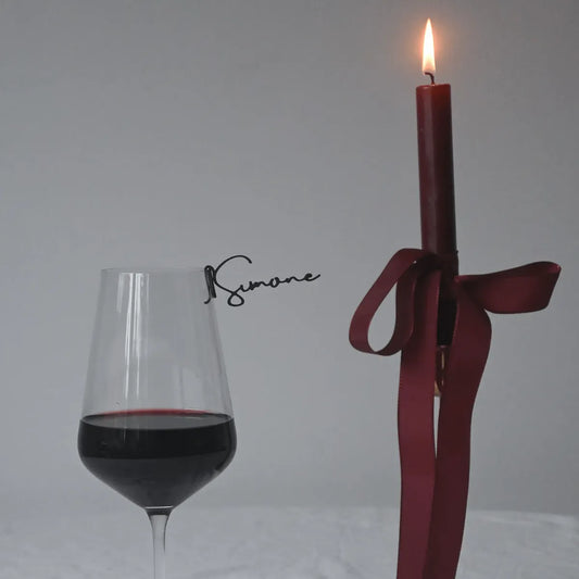 Black personalised drink topper from the champagne collection attached to rim of wine glass filled with red wine